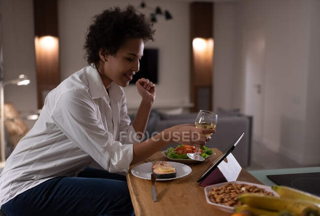 Senhora étnica feliz com vinho propondo brinde ao ter data on-line e jantar — Fotografia de Stock