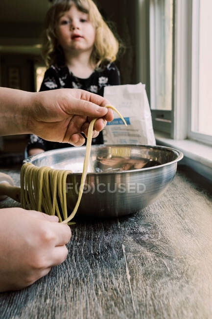 Маленькая девочка смотрит, как ее отец делает пасту — стоковое фото