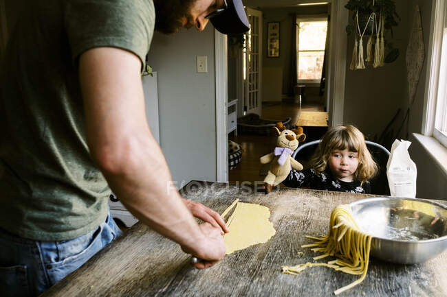 Отец и дочь вместе готовят макароны дома — стоковое фото