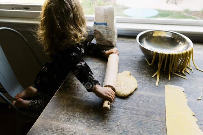 Дівчинка-малюк допомагає з виготовленням макаронних виробів — стокове фото