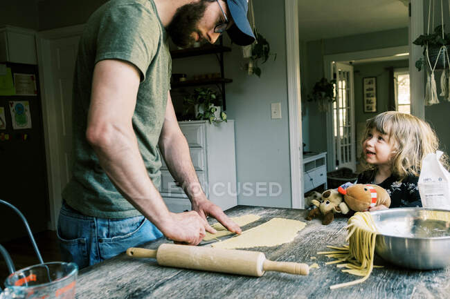 Ein Vater schneidet Nudelteig für Nudeln — Stockfoto