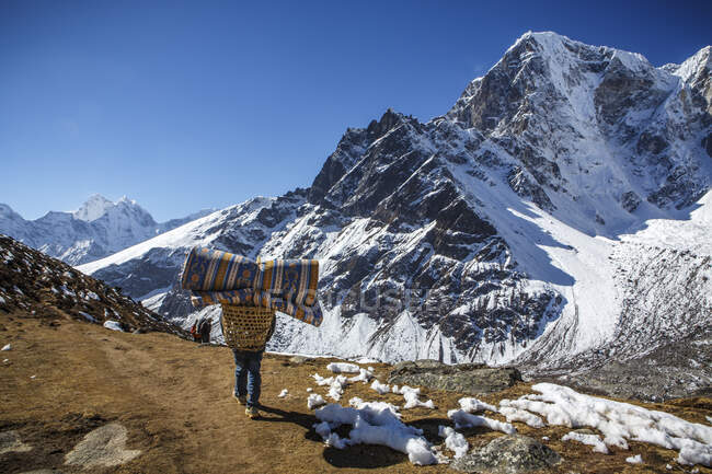 Um porteiro leva suprimentos ao longo da trilha em direção ao Acampamento Base do Everest. — Fotografia de Stock