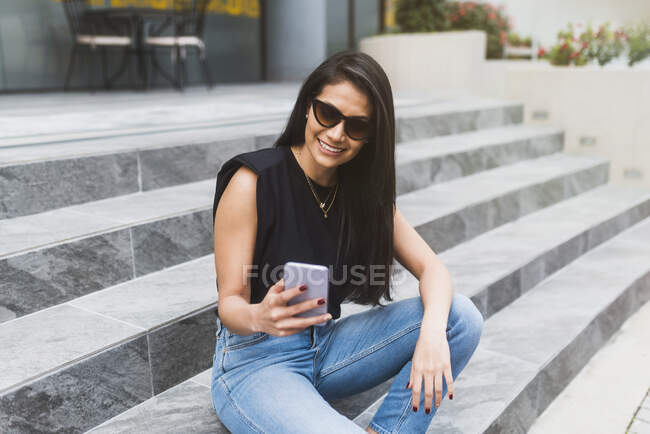 Mulher hispânica digitando no telefone na rua — Fotografia de Stock