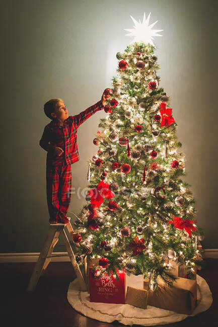 Menino pendurado ornamentos na árvore de Natal à noite — Fotografia de Stock