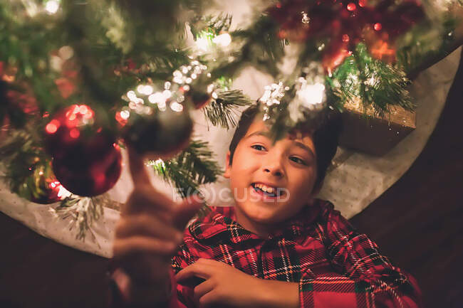 Menino sob a Árvore de Natal à noite — Fotografia de Stock