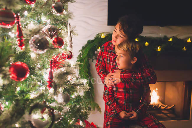 Due fratelli a casa a guardare l'albero di Natale di notte — Foto stock