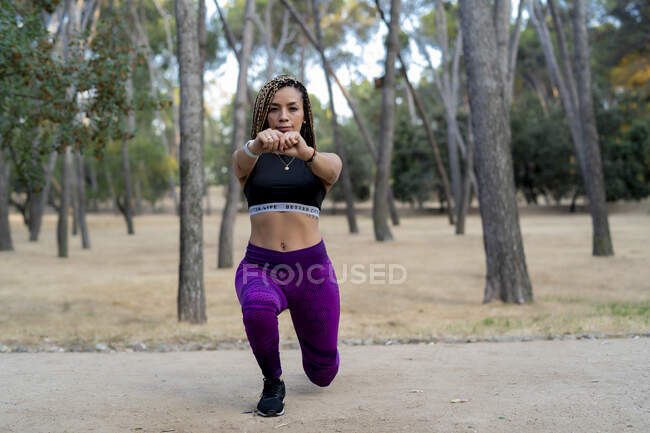 Woman with braids in her hair stretching her legs before running — Stock Photo