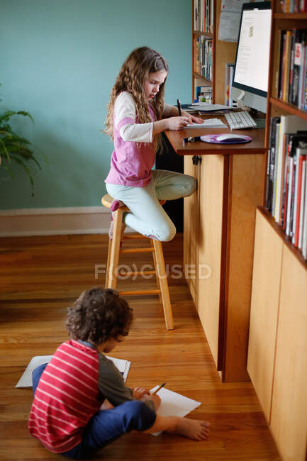 Niños haciendo trabajo escolar en casa durante la pandemia - foto de stock