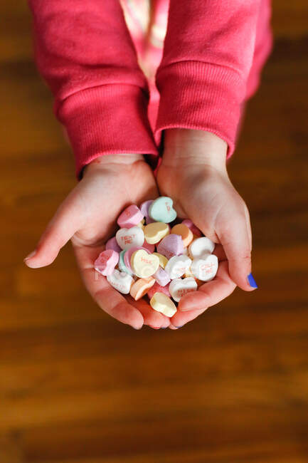 Child's Hands holding candy hearts on Valentine's Day — Stock Photo