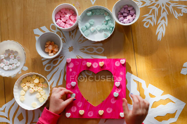Un niño haciendo un marco para el día de San Valentín - foto de stock