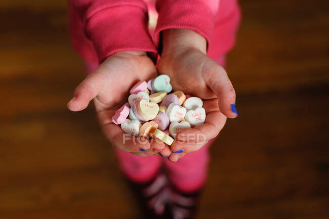 Mani del bambino che tengono i cuori di caramelle a San Valentino — Foto stock