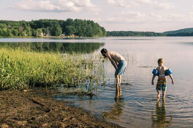 Un padre y un hijo buscando peces en la orilla - foto de stock