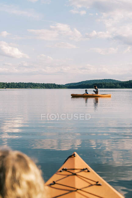 Un père et son fils ouvrent la voie dans leur kayak sur un lac serein — Photo de stock