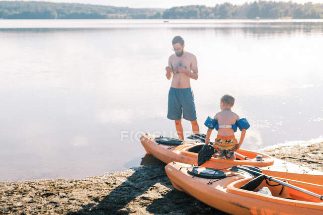 Um pai e um filho se preparando para sua viagem de caiaque no lago — Fotografia de Stock