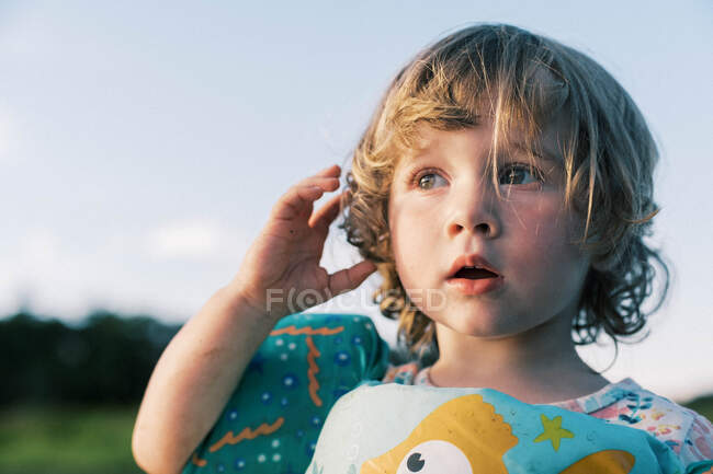 Una niña junto al agua escuchando los sonidos de la naturaleza - foto de stock