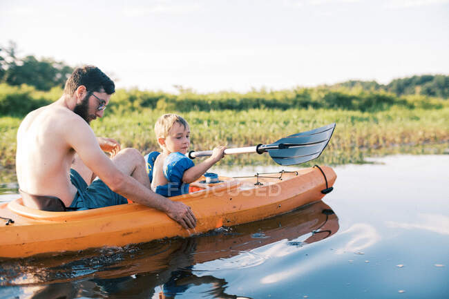 A father and son traveling in their kayak on a river together — Stock Photo