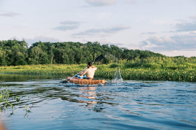 Um pai e um filho viajando um rio juntos em seu caiaque ao pôr do sol — Fotografia de Stock