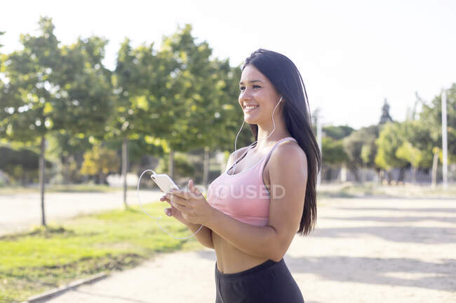 Giovane corridore femminile mettere la musica sul telefono cellulare prima di esercitare — Foto stock