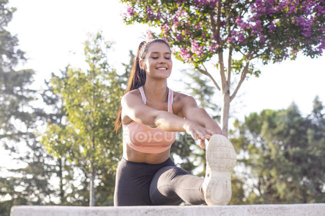 Young female runner doing stretches in the park after running — Stock Photo