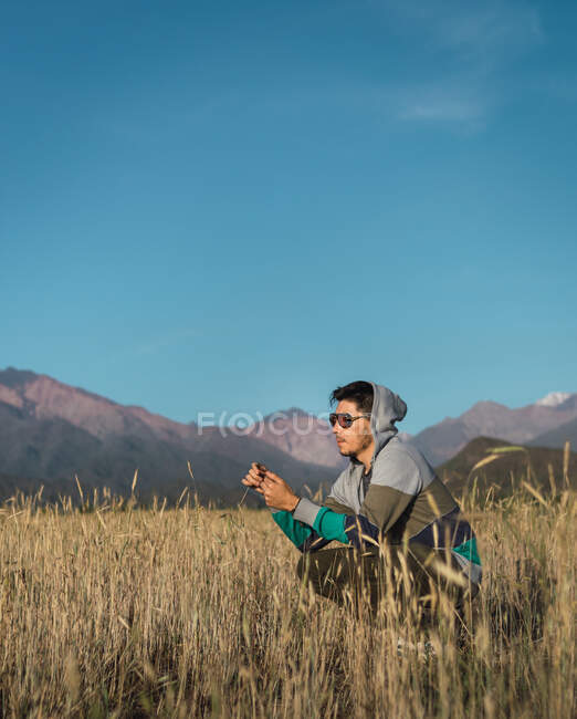 Jovem sentado em um campo ao lado das montanhas dos Andes — Fotografia de Stock