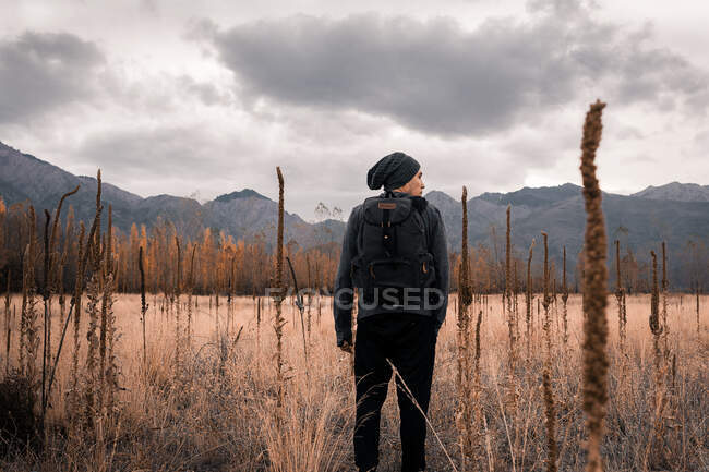 Hombre de pie en el campo frente a las montañas - foto de stock