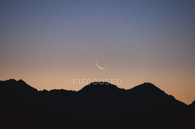 Lua no céu liso acima das montanhas — Fotografia de Stock