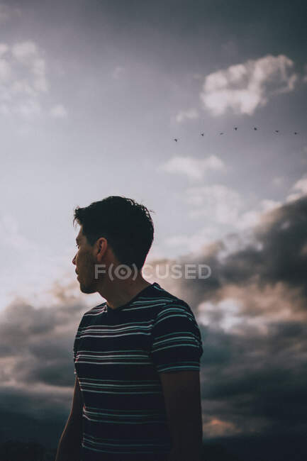 Joven adulto mirando el horizonte entre las nubes - foto de stock