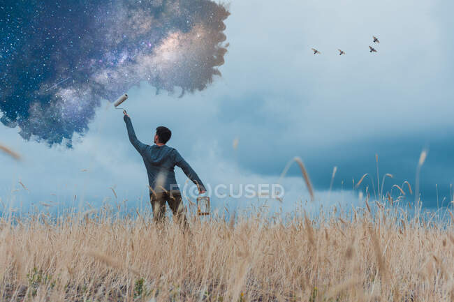 Hombre pintando estrellas en el paisaje rural - foto de stock