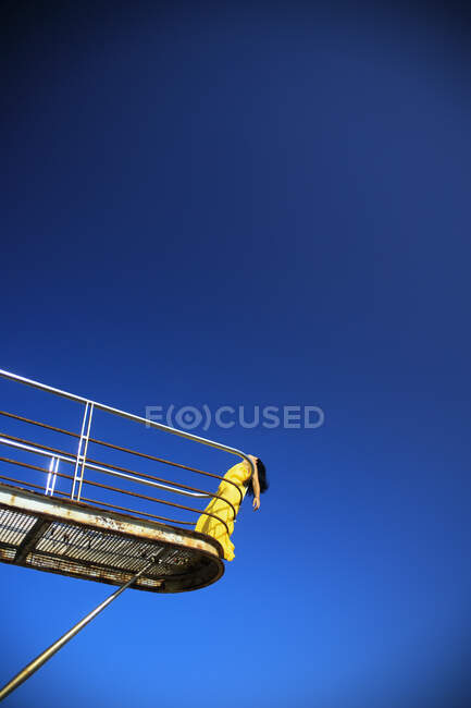 Uma jovem de terno amarelo apoiada em uma ponte — Fotografia de Stock