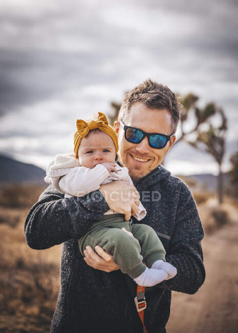 Un hombre con un bebé está de pie en un desierto de California - foto de stock