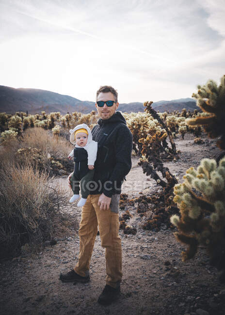 Um homem com um bebé está num deserto da Califórnia. — Fotografia de Stock