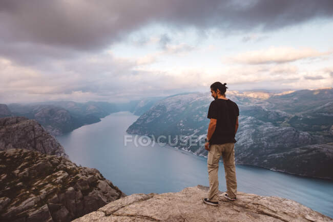 Homem de pé e olhando para baixo na borda do penhasco em Preikestolen, Noruega — Fotografia de Stock