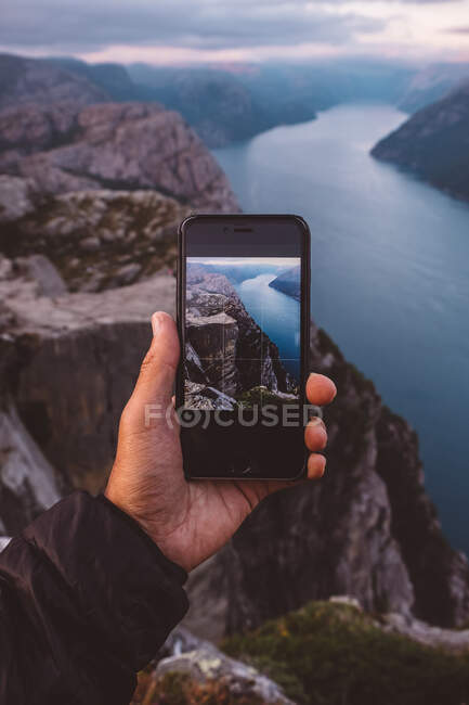 Рука тримає смартфон з зображенням сцени на фоні в Норвезьких фіордах. — стокове фото