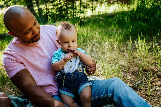 Father looking at infant son outside in nature — Stock Photo