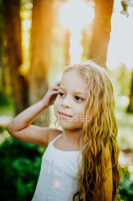 Retrato vertical brillante de niña con la mano en el pelo - foto de stock
