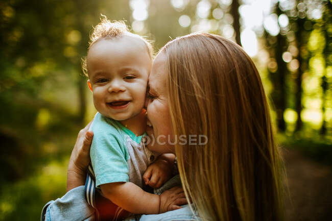 Щаслива мама лоскоче хлопчика зовні в лісі — стокове фото