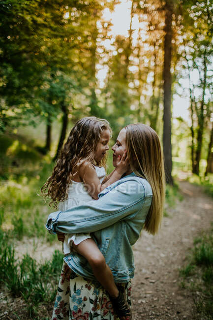 Felice madre tenendo giovane ragazza nella foresta — Foto stock