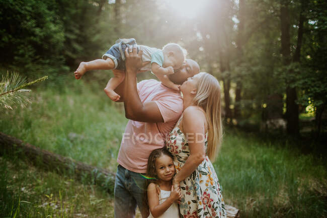 Vierköpfige Familie kuschelt und küsst sich im Wald — Stockfoto
