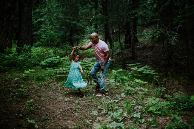 Padre e hija bailando en medio del bosque - foto de stock