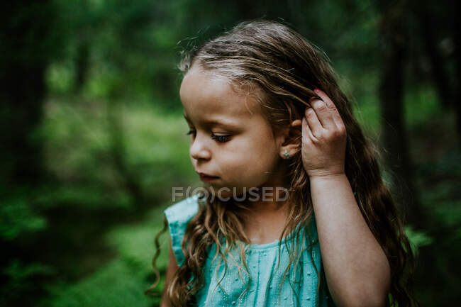 Молодая двуличная девушка смотрит вниз и чинит волосы — стоковое фото