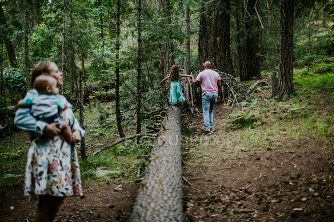 Father helping daughter walk on log while mom watches — Stock Photo