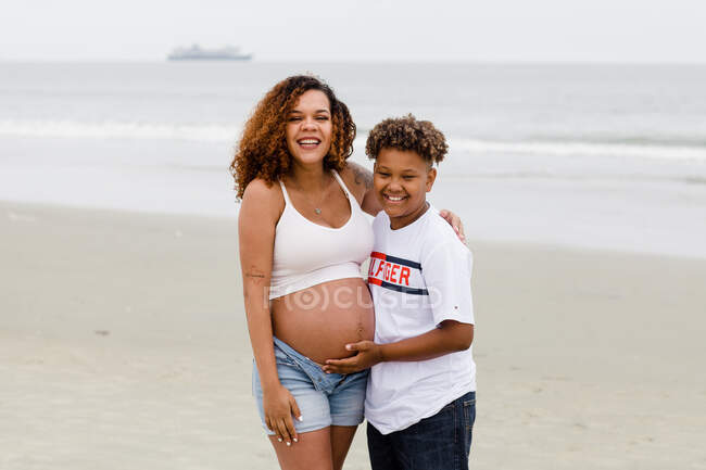 Брат позує з вагітною сестрою на пляжі — стокове фото