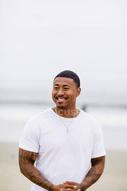 Hombre de raza mixta sonriendo en la playa - foto de stock
