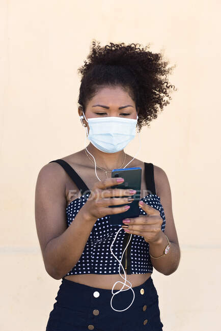 Femme noire avec masque gère son téléphone mobile — Photo de stock