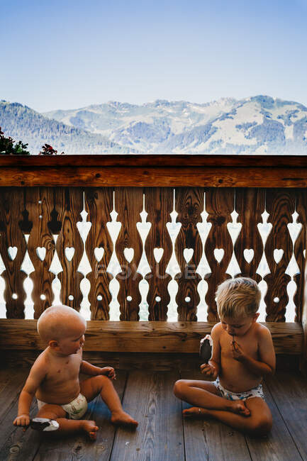 Діти їдять морозиво на балконі з горами позаду влітку — стокове фото