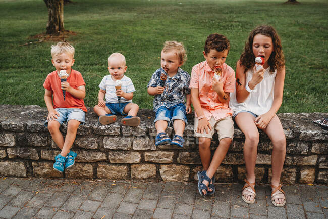 Familia blanca y niños comiendo helado juntos durante las vacaciones - foto de stock