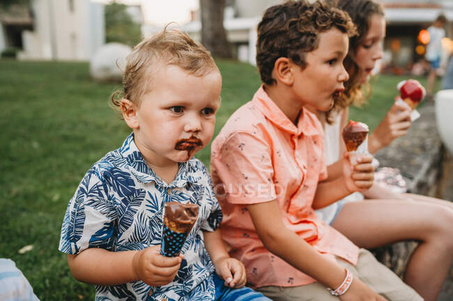 Siblings with dirty faces eating ice cream together during vacation — Stock Photo