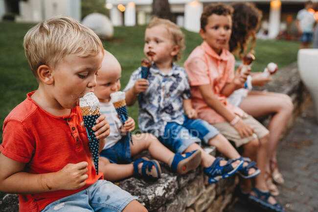 Niños pequeños de una familia comiendo helado ensuciándose y ensuciándose - foto de stock