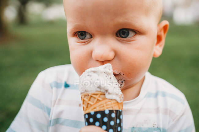 White baby with blue eyes eating ice cream with dirty mouth — Stock Photo