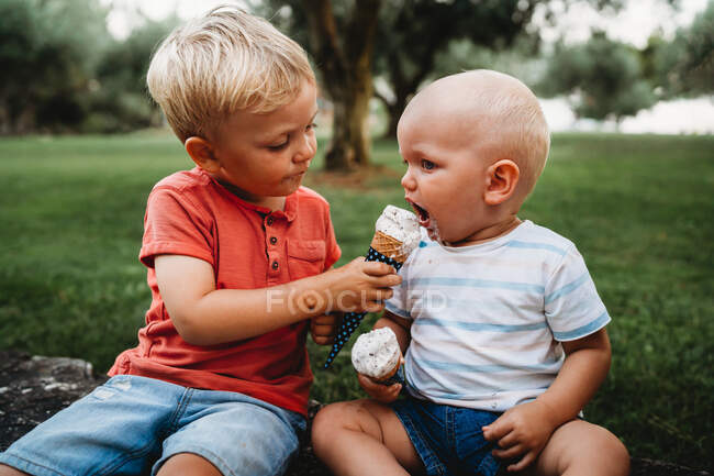 Jovem criança branca dando sorvete irmão em um dia quente de verão — Fotografia de Stock